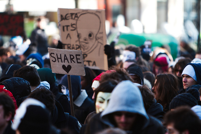 Une foule portant un panneau où il est inscrit "share" (partage).